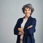 Studio portrait of a confident mature woman posing against a gray background